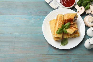 Photo of Delicious rolled crepes with mushrooms, basil and sauce on light blue wooden table, flat lay. Space for text