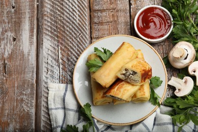 Photo of Delicious rolled crepes with mushrooms, parsley and sauce on wooden table, flat lay. Space for text