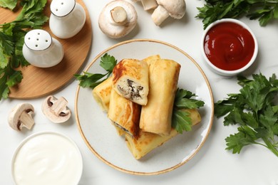 Photo of Delicious rolled crepes with mushrooms, parsley, sauce and sour cream on white marble table, flat lay