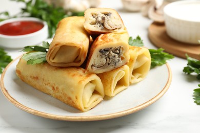 Photo of Delicious rolled crepes with mushrooms, parsley, sauce and sour cream on white marble table, closeup