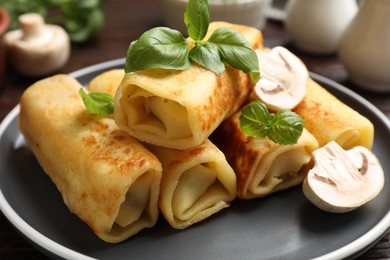 Photo of Delicious rolled crepes with mushrooms and basil on table, closeup