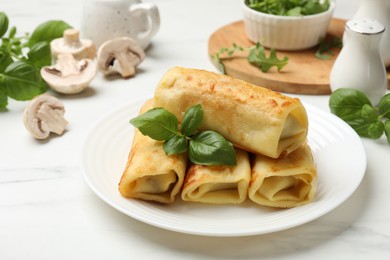 Photo of Delicious rolled crepes with basil and mushrooms on white marble table, closeup