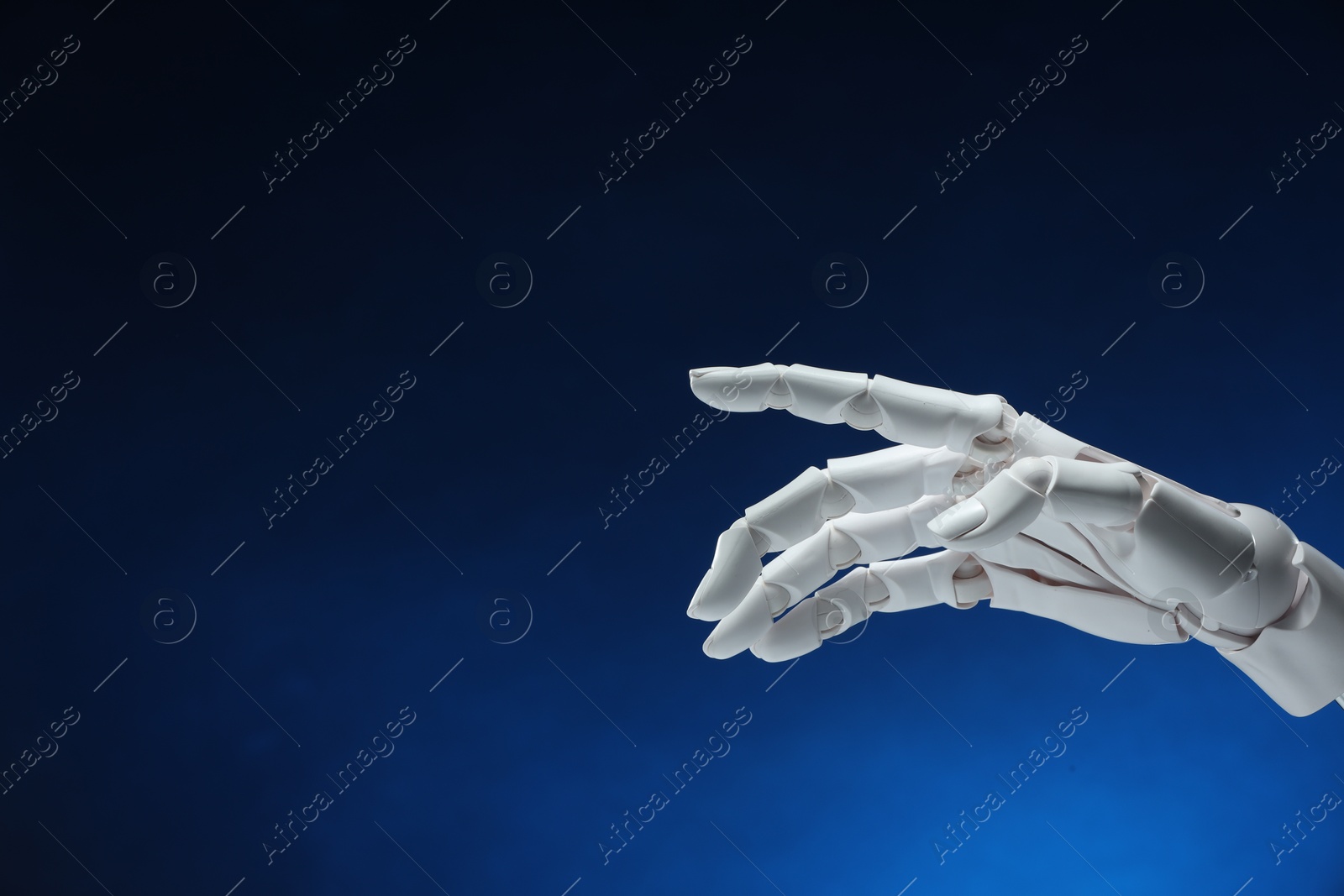 Photo of Artificial intelligence. Robot hand pointing at something on dark blue background, space for text