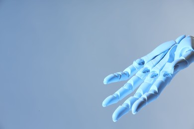 Photo of Artificial intelligence. Robot hand gesturing on pale light blue background, space for text