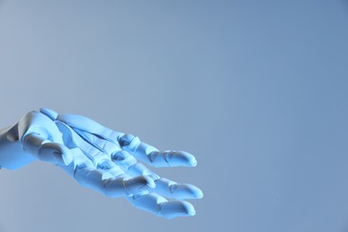 Photo of Artificial intelligence. Robot hand gesturing on pale light blue background, space for text