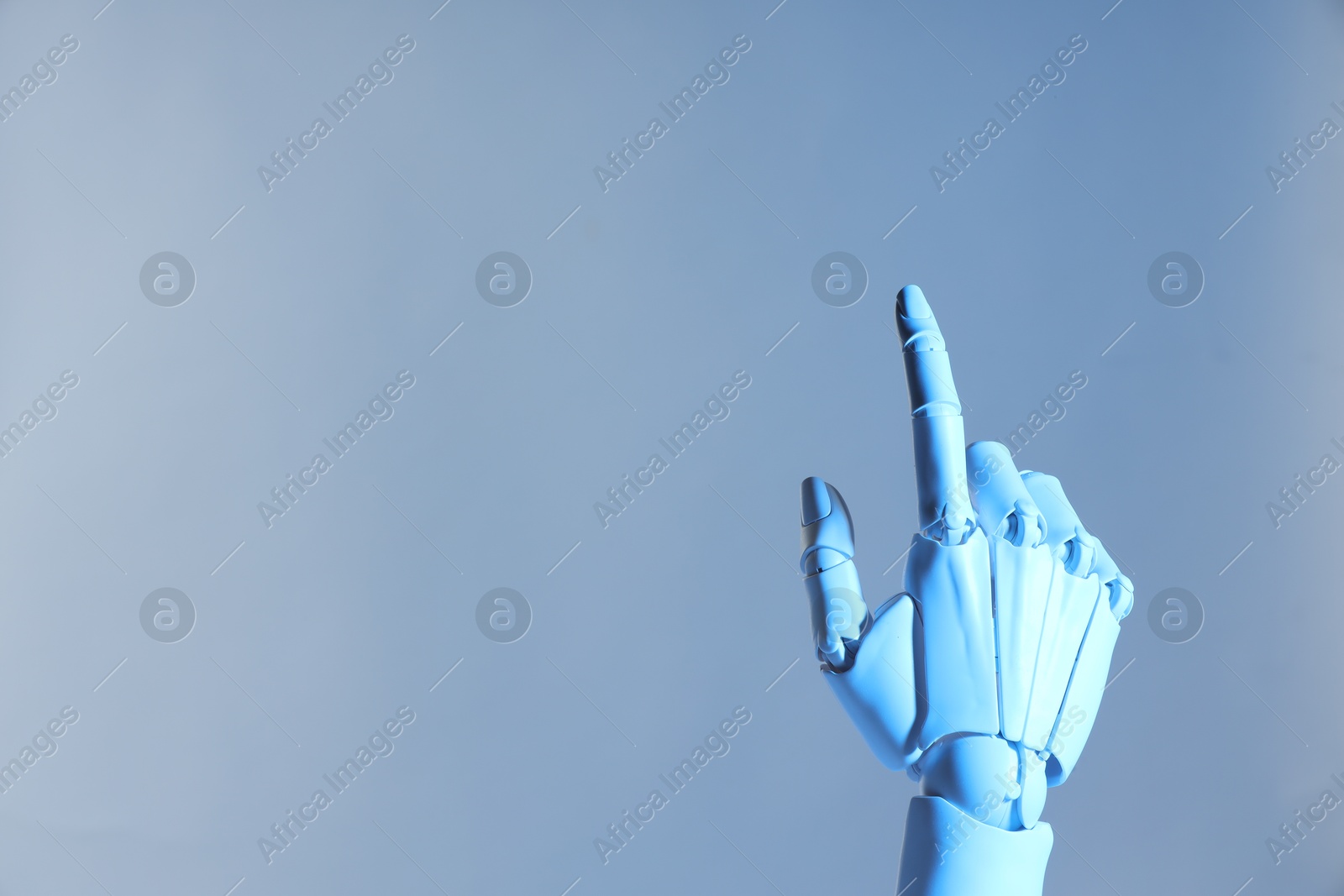 Photo of Artificial intelligence. Robot hand pointing at something on pale light blue background, space for text