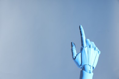 Photo of Artificial intelligence. Robot hand pointing at something on pale light blue background, space for text