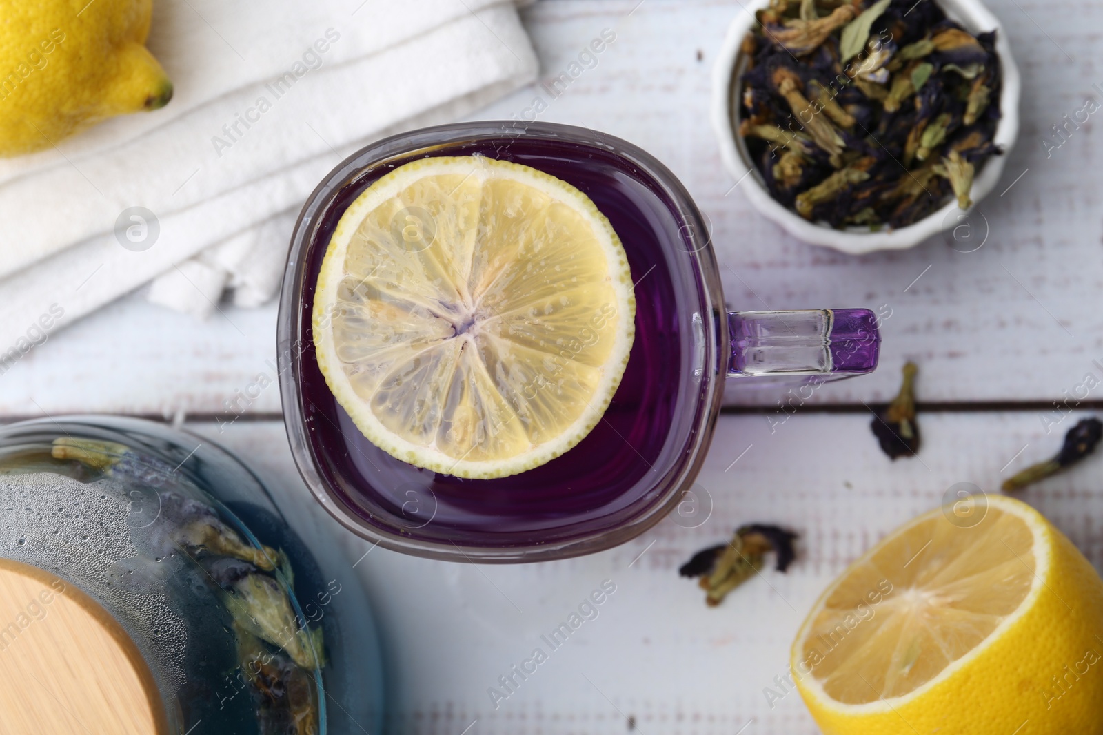 Photo of Delicious butterfly pea flower tea with lemon on wooden table, flat lay