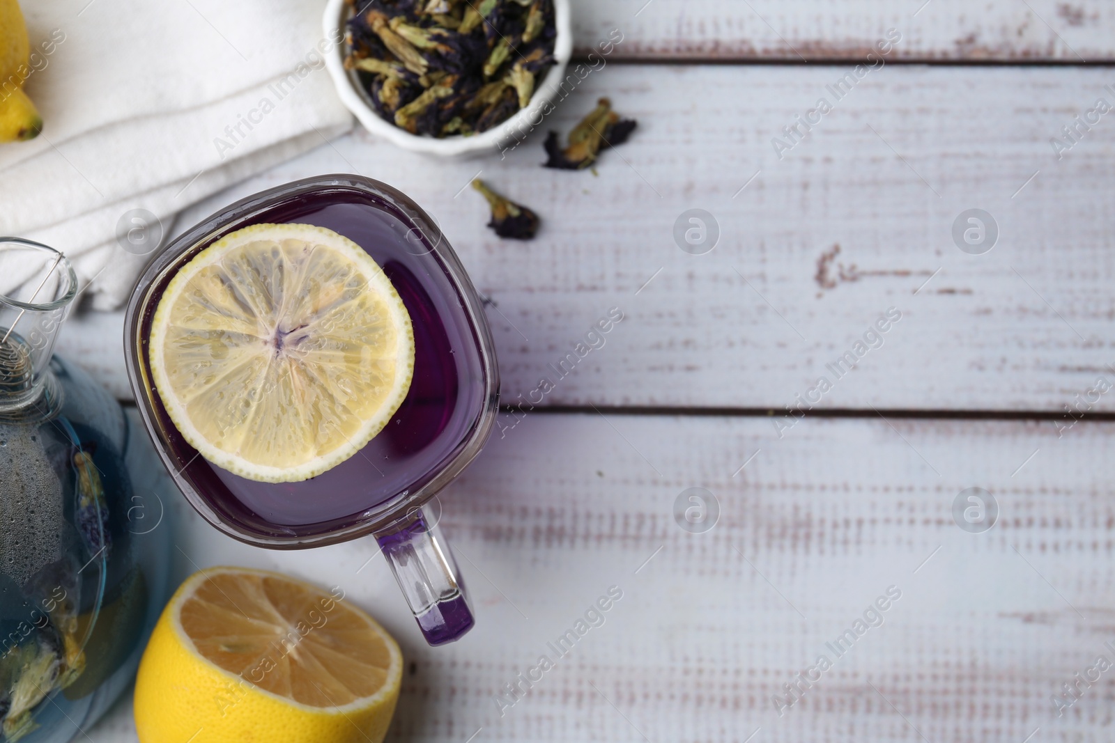 Photo of Delicious butterfly pea flower tea with lemon on wooden table, flat lay. Space for text