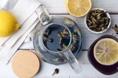 Photo of Delicious butterfly pea flower tea with lemon on wooden table, flat lay