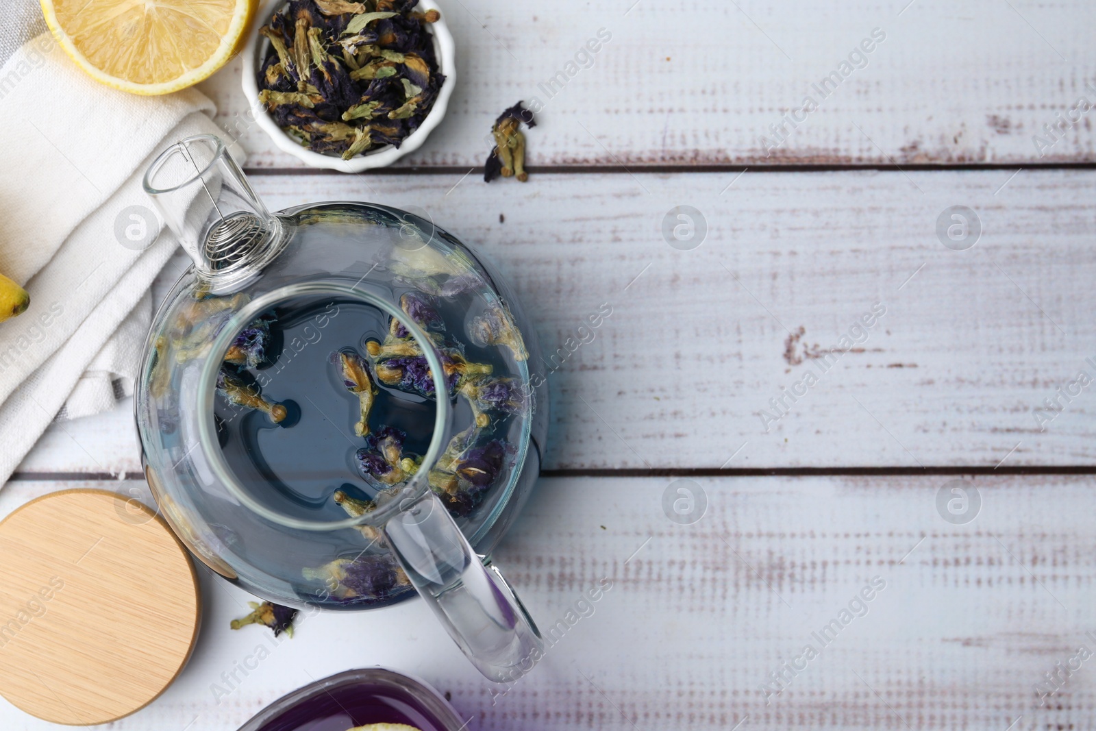 Photo of Delicious butterfly pea flower tea with lemon on wooden table, flat lay. Space for text