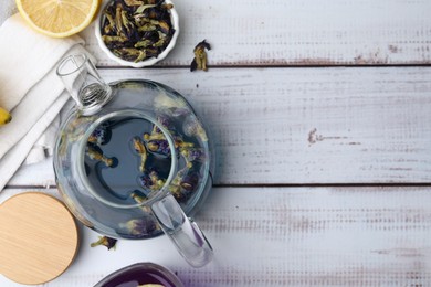 Delicious butterfly pea flower tea with lemon on wooden table, flat lay. Space for text