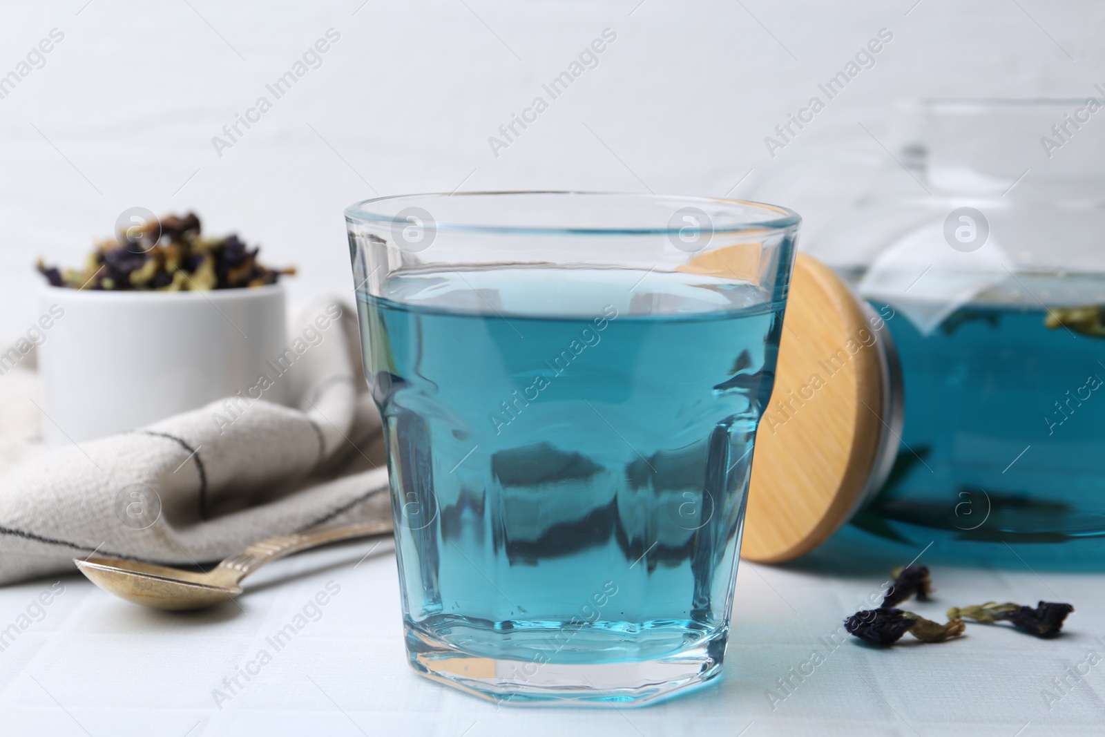 Photo of Delicious butterfly pea flower tea on white tiled table, closeup