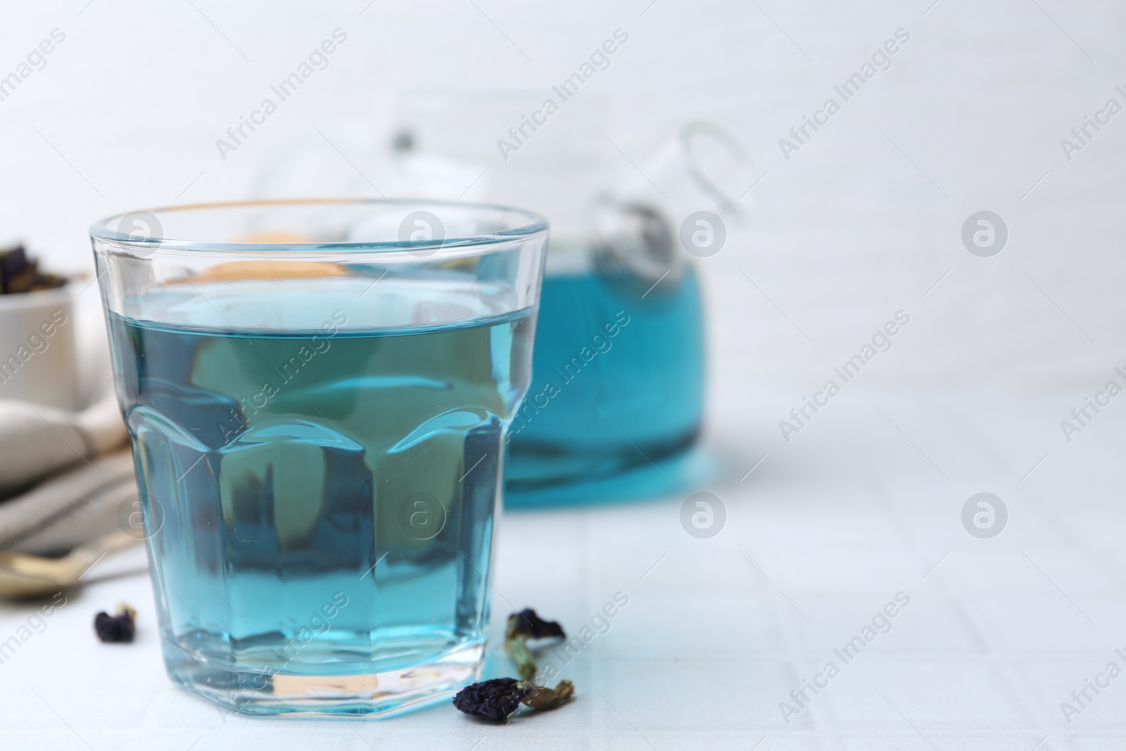 Photo of Delicious butterfly pea flower tea on white tiled table. Space for text