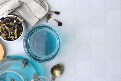 Delicious butterfly pea flower tea on white tiled table, flat lay. Space for text