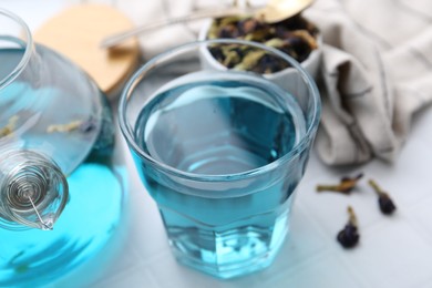 Delicious butterfly pea flower tea on white tiled table, closeup