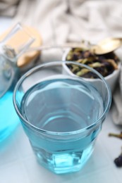 Delicious butterfly pea flower tea on white tiled table, closeup