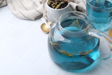 Photo of Delicious butterfly pea flower tea on white tiled table, closeup. Space for text