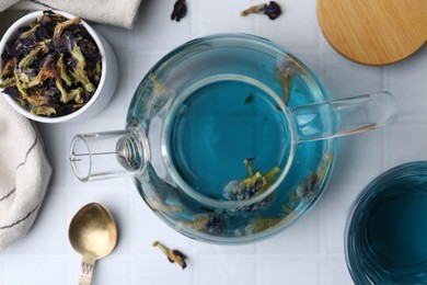 Delicious butterfly pea flower tea on white tiled table, flat lay