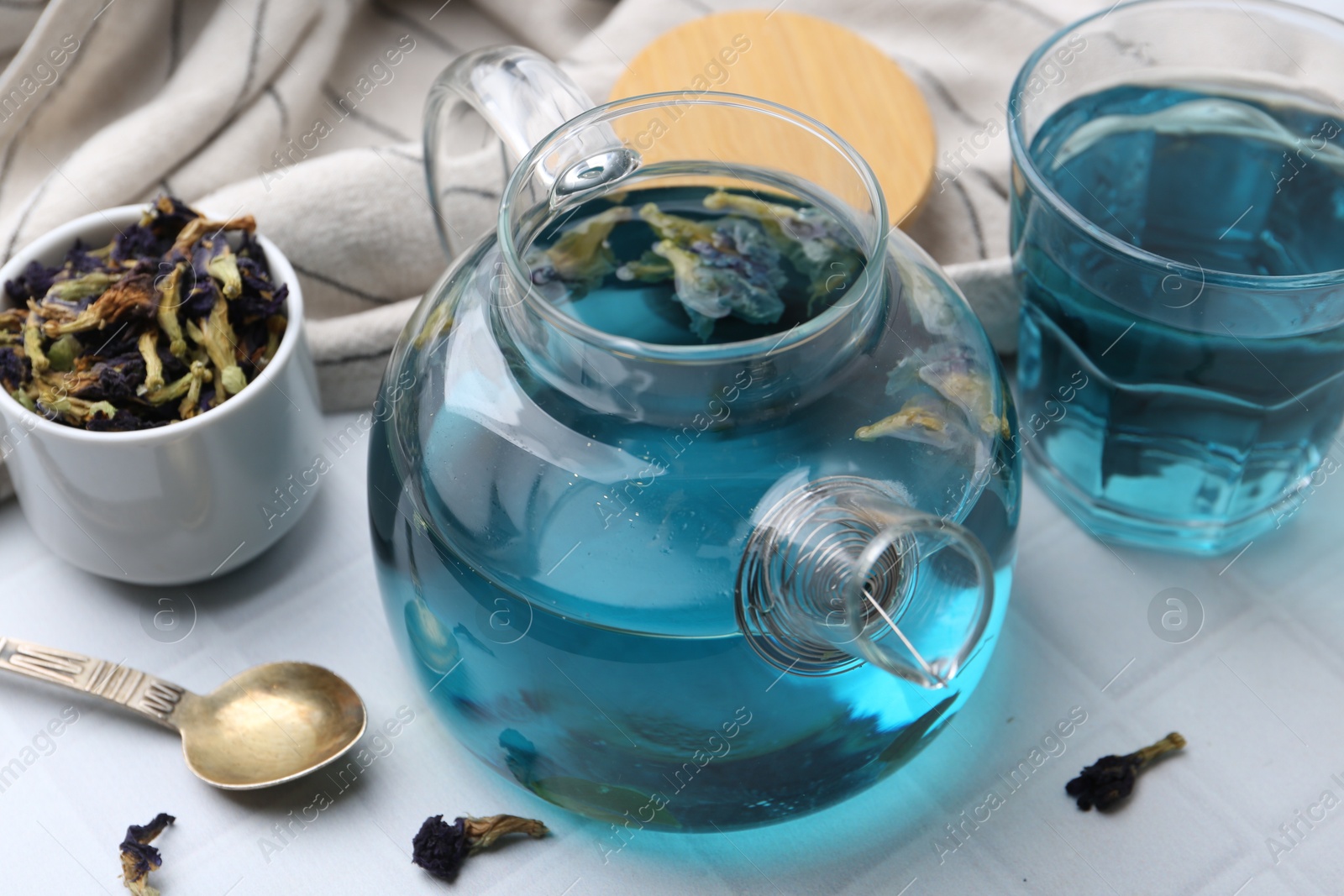 Photo of Delicious butterfly pea flower tea on white tiled table, closeup