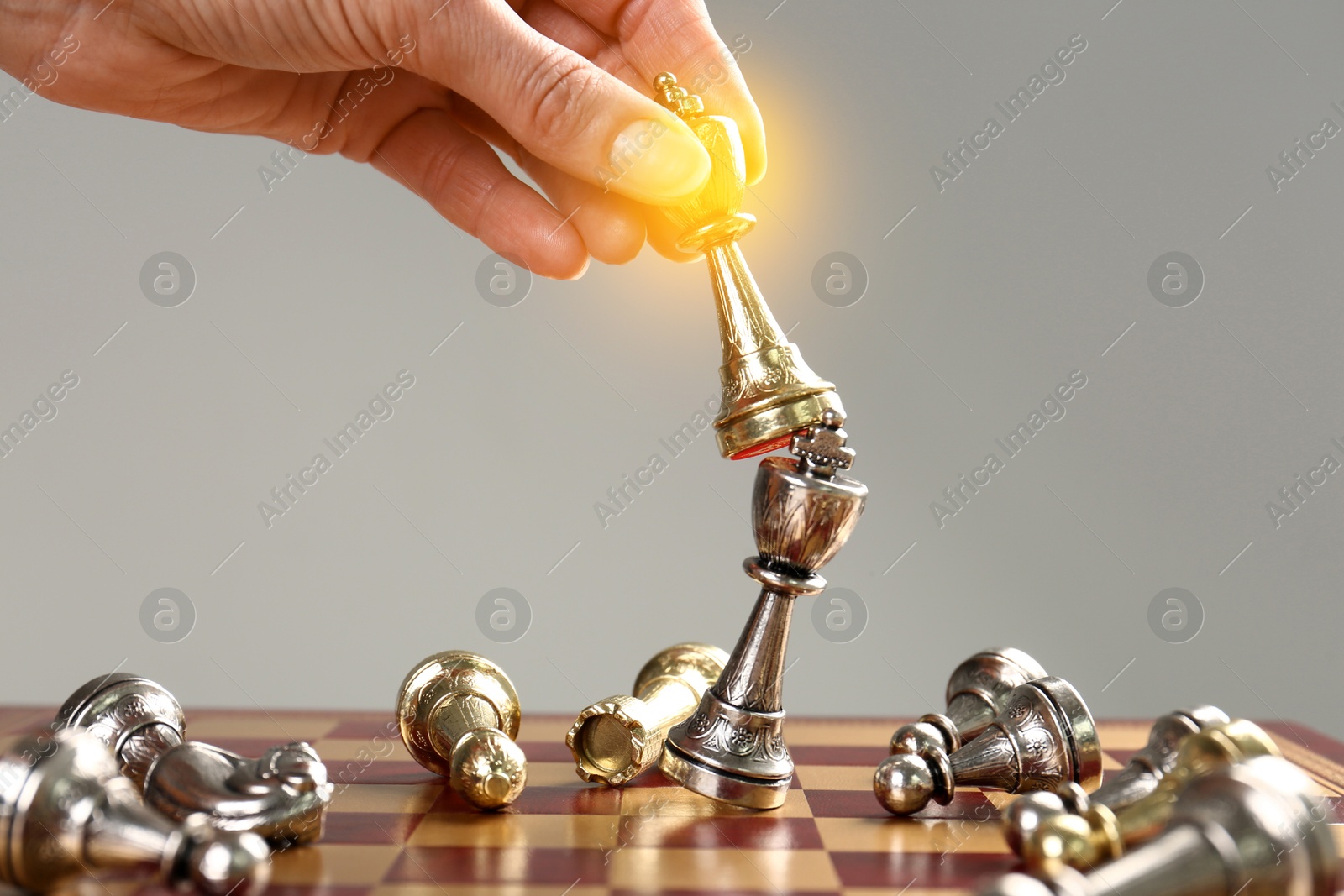 Image of Woman winning game and hitting opponent's king with chess piece in her hand on chessboard, closeup