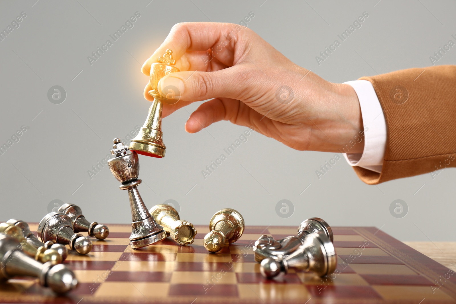 Image of Woman winning game and hitting opponent's king with chess piece in her hand on chessboard, closeup