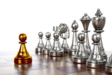 Image of Golden pawn standing in front of silver chess pieces on wooden chessboard