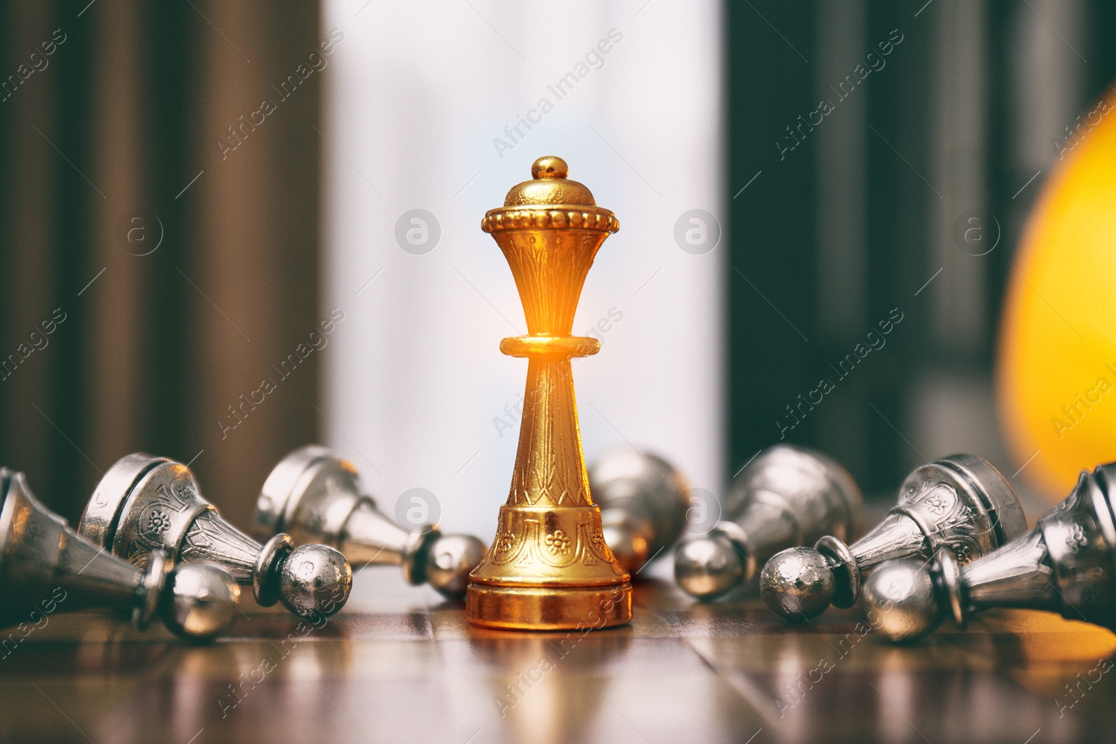 Image of Golden queen standing among bowing pawns on wooden chessboard indoors