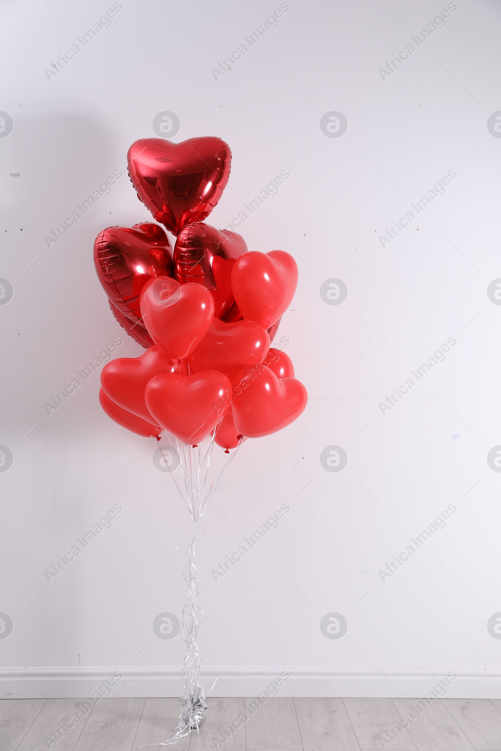 Photo of Bunch of heart shaped balloons near white wall. Valentine's day celebration