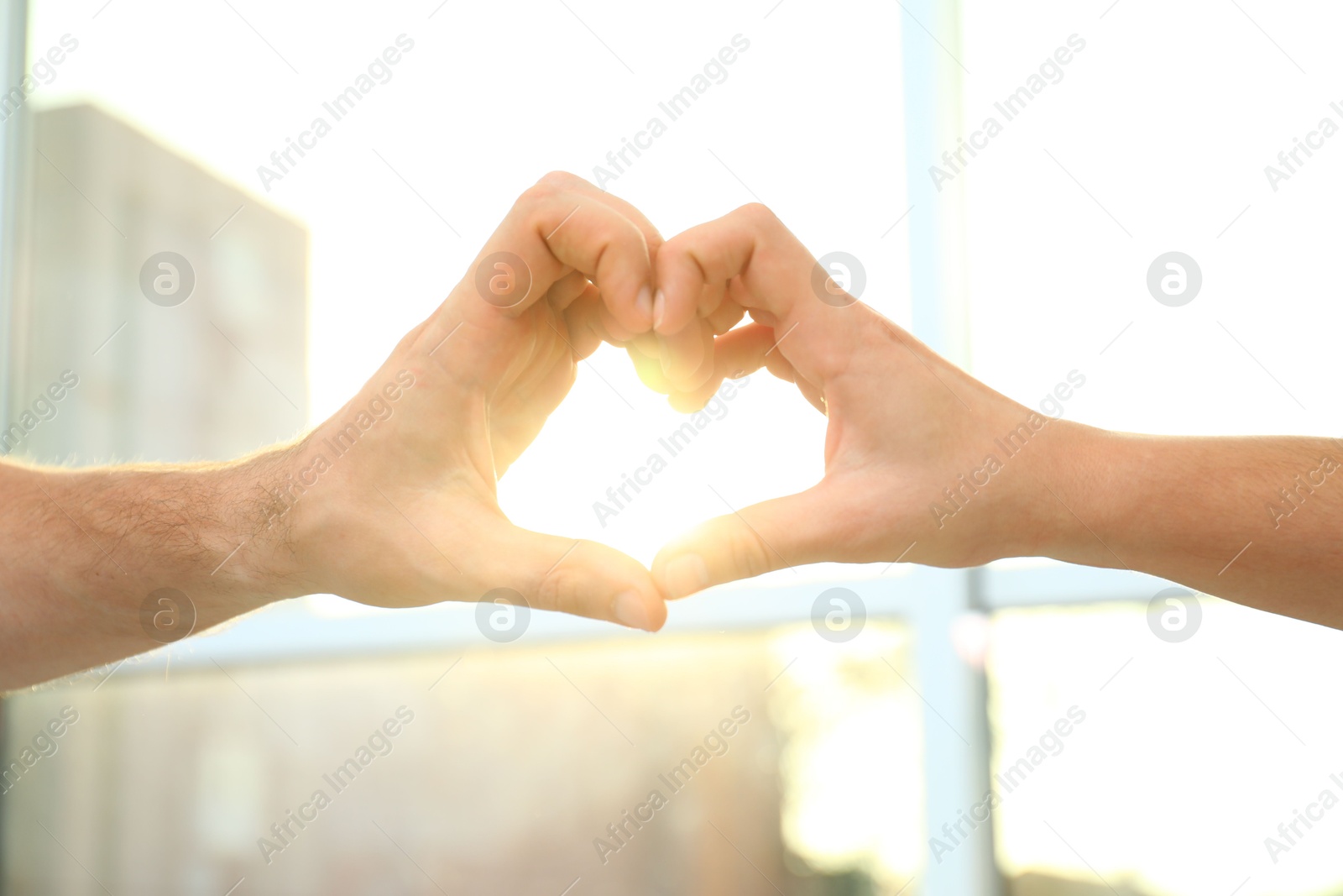 Photo of Young people forming heart with hands indoors, closeup. Happy family