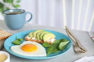 Photo of Romantic breakfast with heart shaped fried egg served on light grey kitchen table