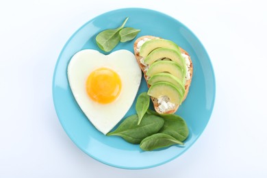 Photo of Plate of tasty breakfast with heart shaped fried egg isolated on white, top view