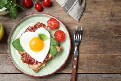 Photo of Tasty sandwich with heart shaped fried egg and bacon on wooden table, flat lay. Space for text