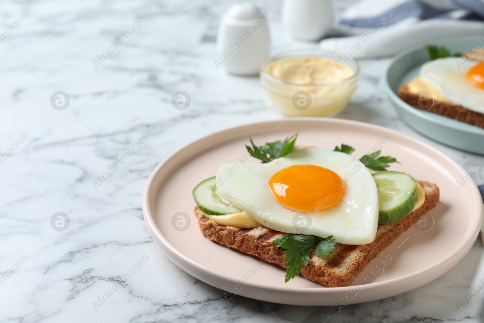 Photo of Plate of tasty sandwich with heart shaped fried egg on white marble table