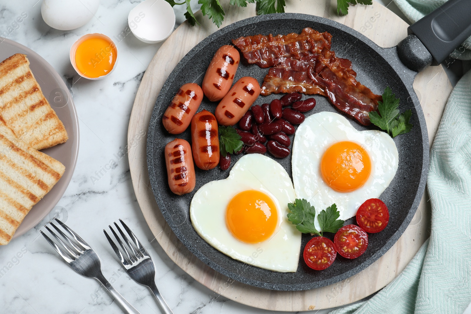 Photo of Delicious breakfast with heart shaped fried eggs and  sausages served on white marble table, flat lay