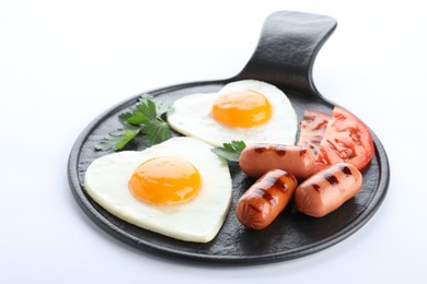 Photo of Slate plate of tasty breakfast with heart shaped fried eggs and sausages isolated on white