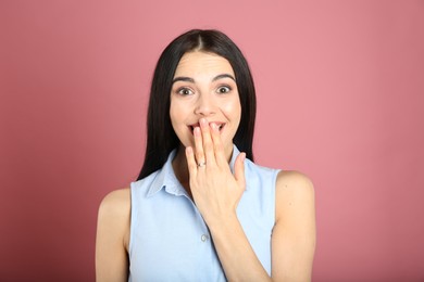 Photo of Emotional woman wearing beautiful engagement ring on pink background