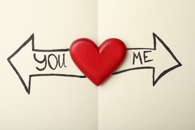 Photo of Heart between arrows with words YOU and ME pointing in different directions on notepad, top view. Composition symbolizing relationship problems