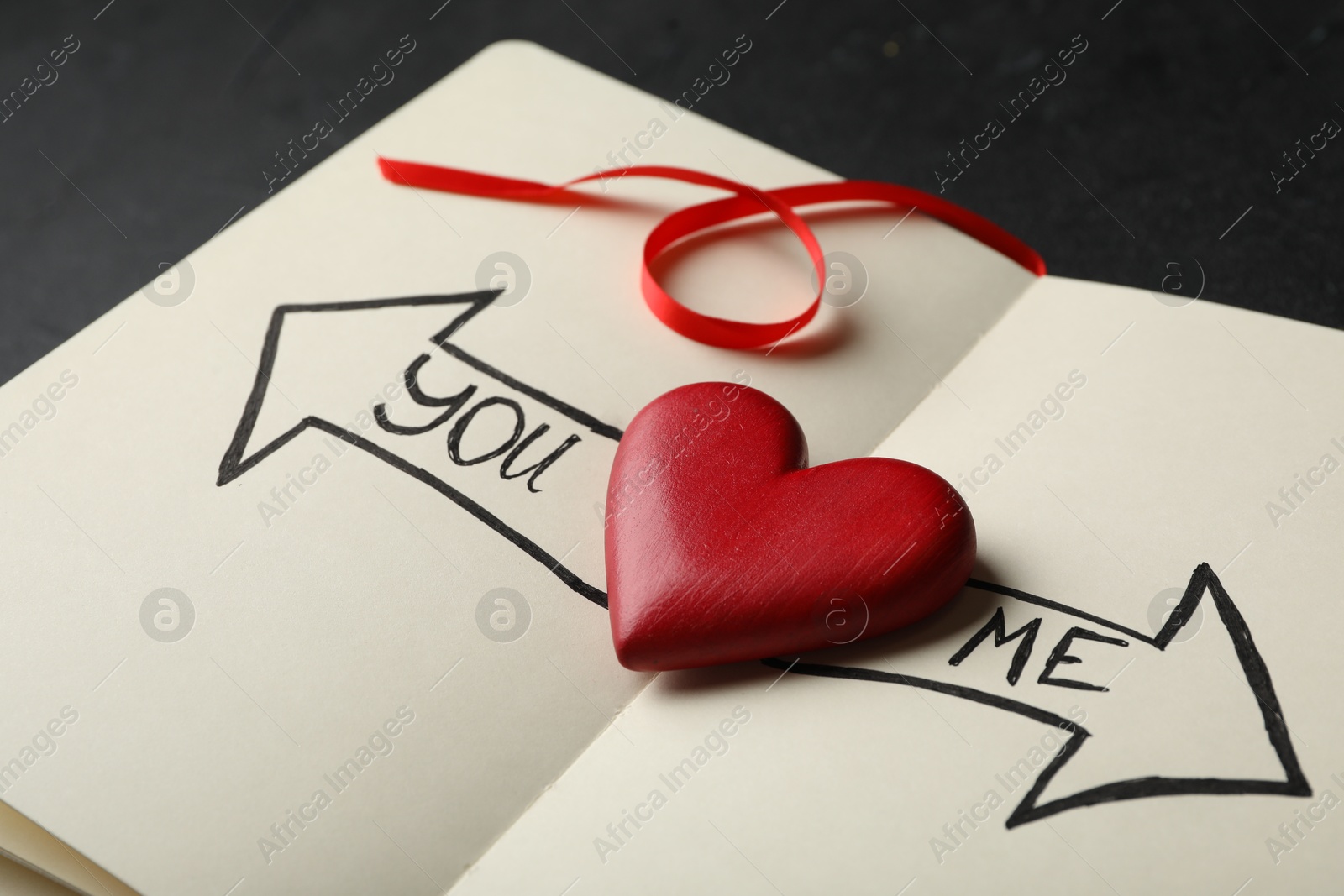 Photo of Heart between arrows with words YOU and ME pointing in different directions on notepad. Composition symbolizing relationship problems