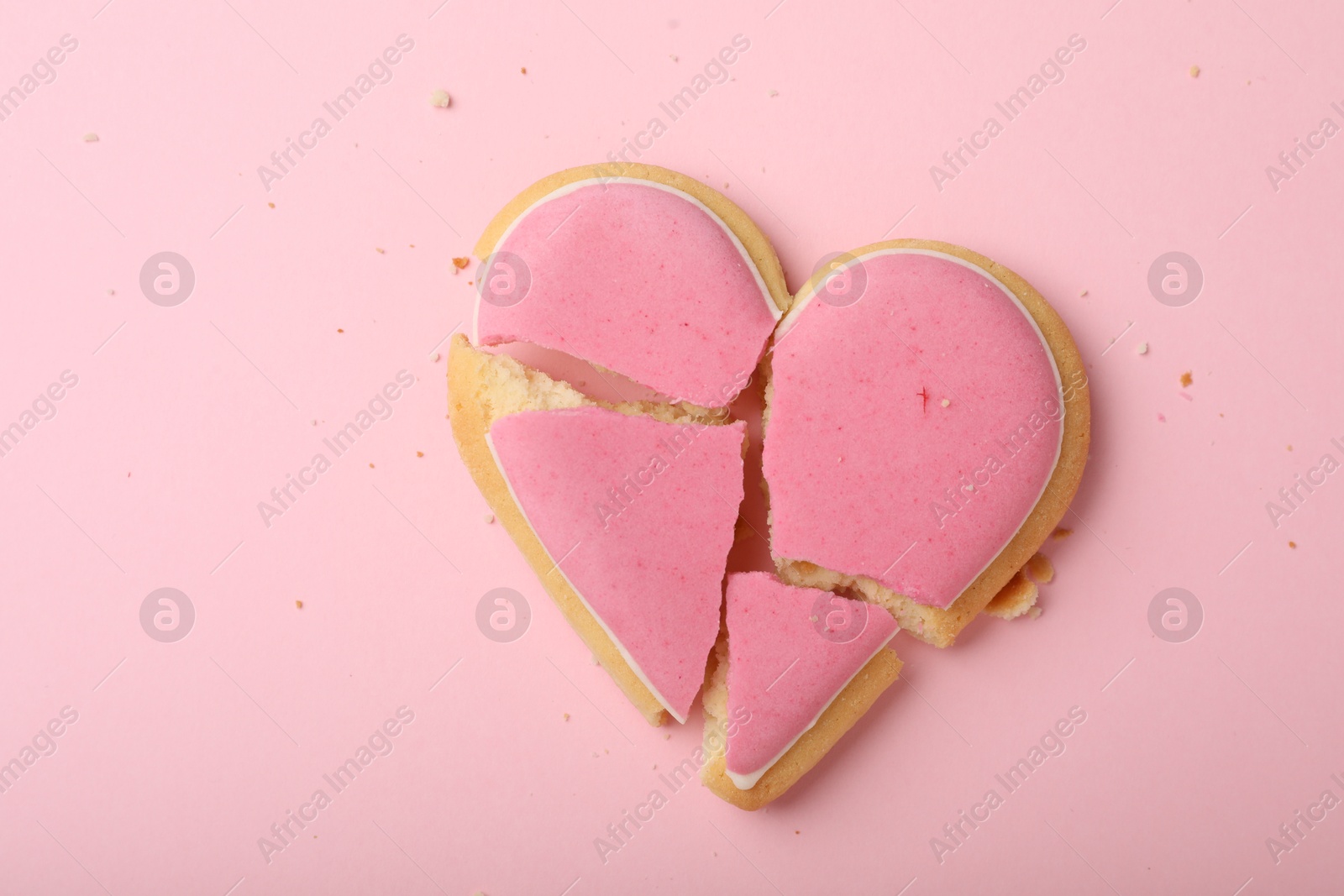 Photo of Broken heart shaped cookie on pink background, top view. Relationship problems concept