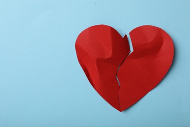 Photo of Torn paper heart on light blue background, top view with space for text. Relationship problems concept