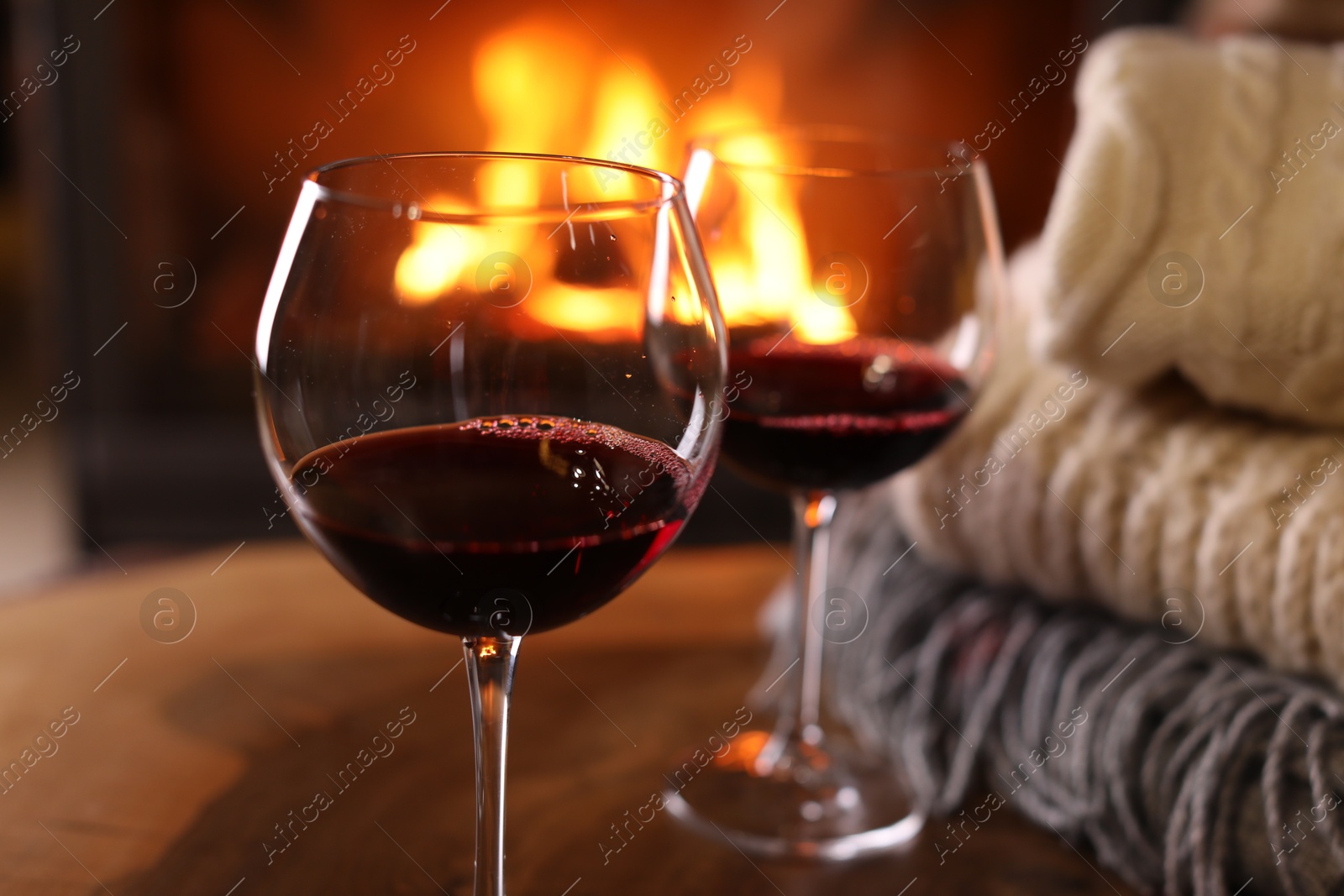 Photo of Glasses of wine, knitwear and blurred fireplace on background