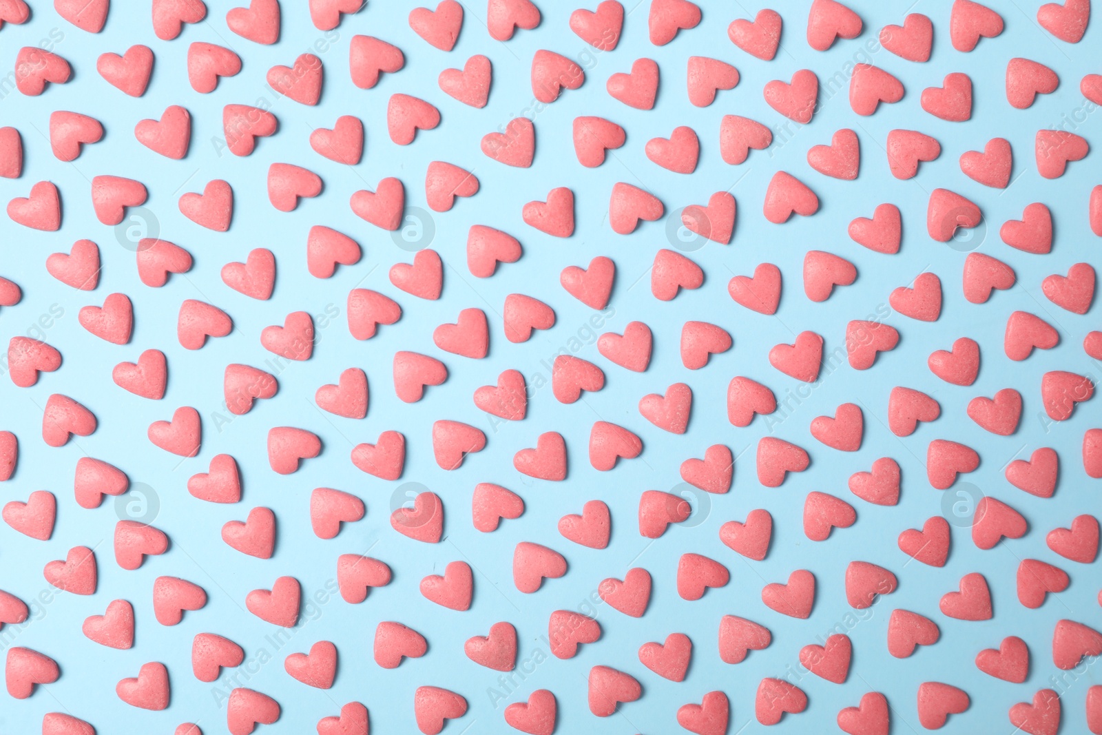 Photo of Bright heart shaped sprinkles on light blue background, flat lay