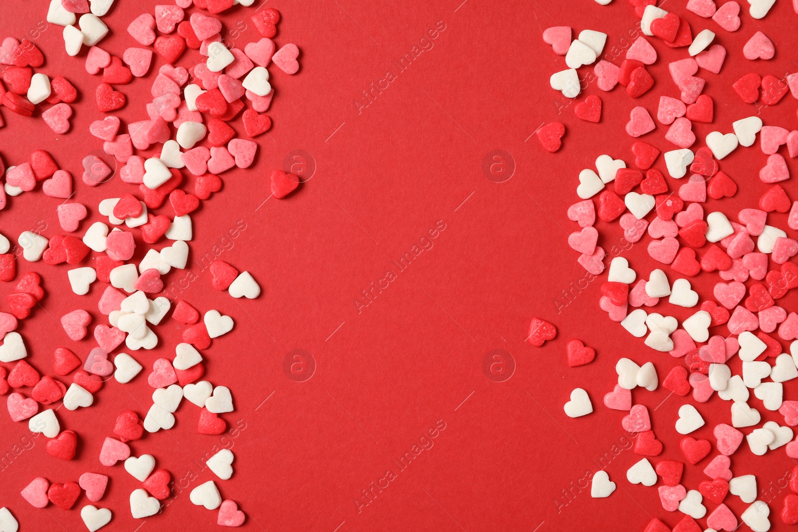 Photo of Bright heart shaped sprinkles on red background, flat lay. Space for text