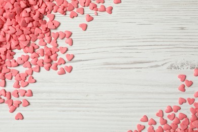 Photo of Pink heart shaped sprinkles on white wooden table, flat lay. Space for text