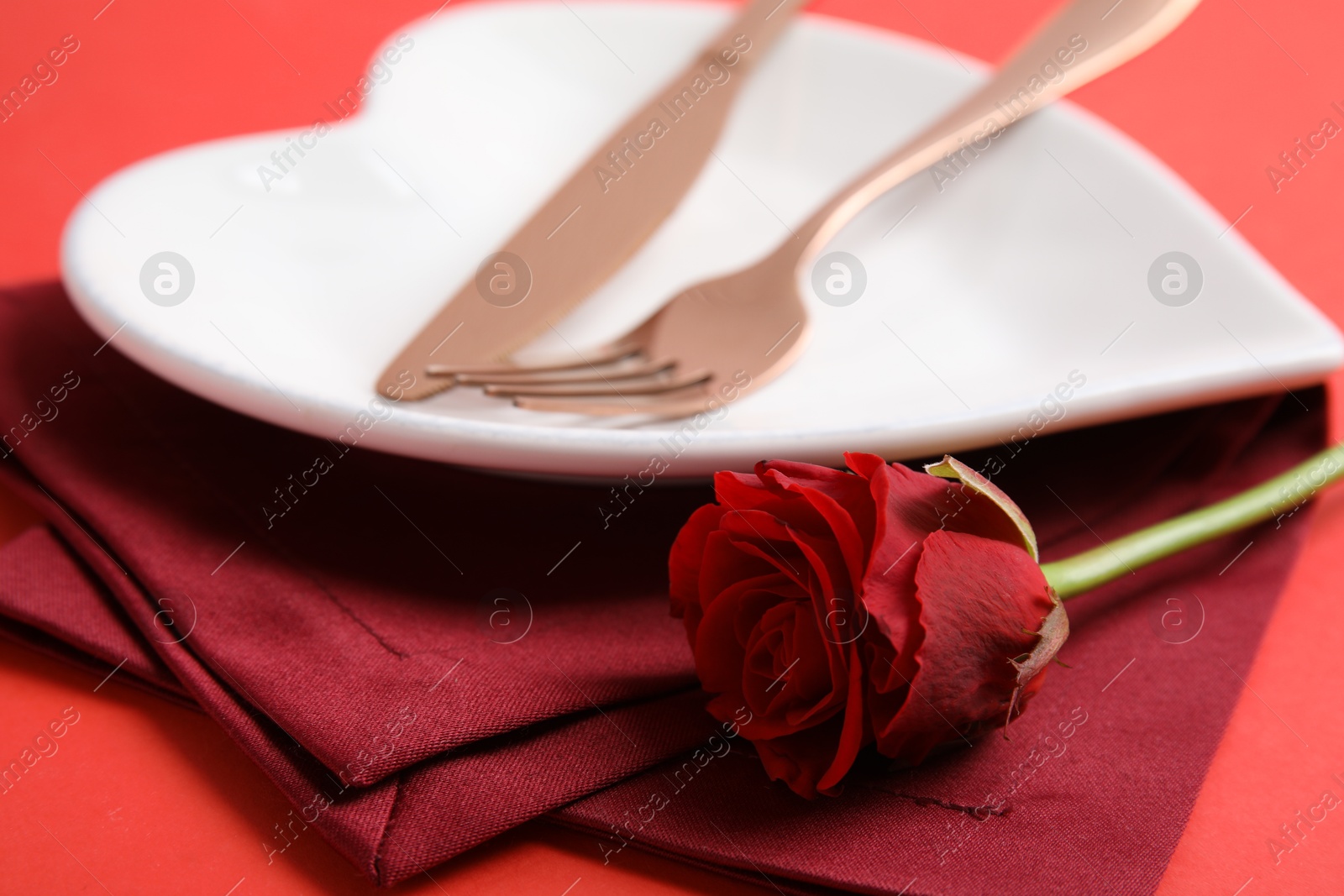 Photo of Elegant table setting for romantic dinner on red background, closeup. Valentine's day celebration