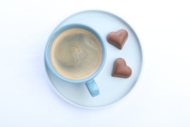 Photo of Romantic breakfast with cup of coffee and chocolate candies isolated on white, top view. Valentine's day celebration