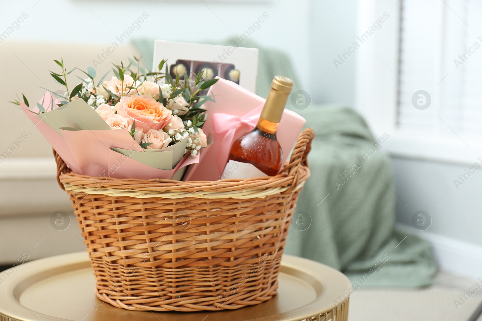 Photo of Wicker basket with gifts on table indoors