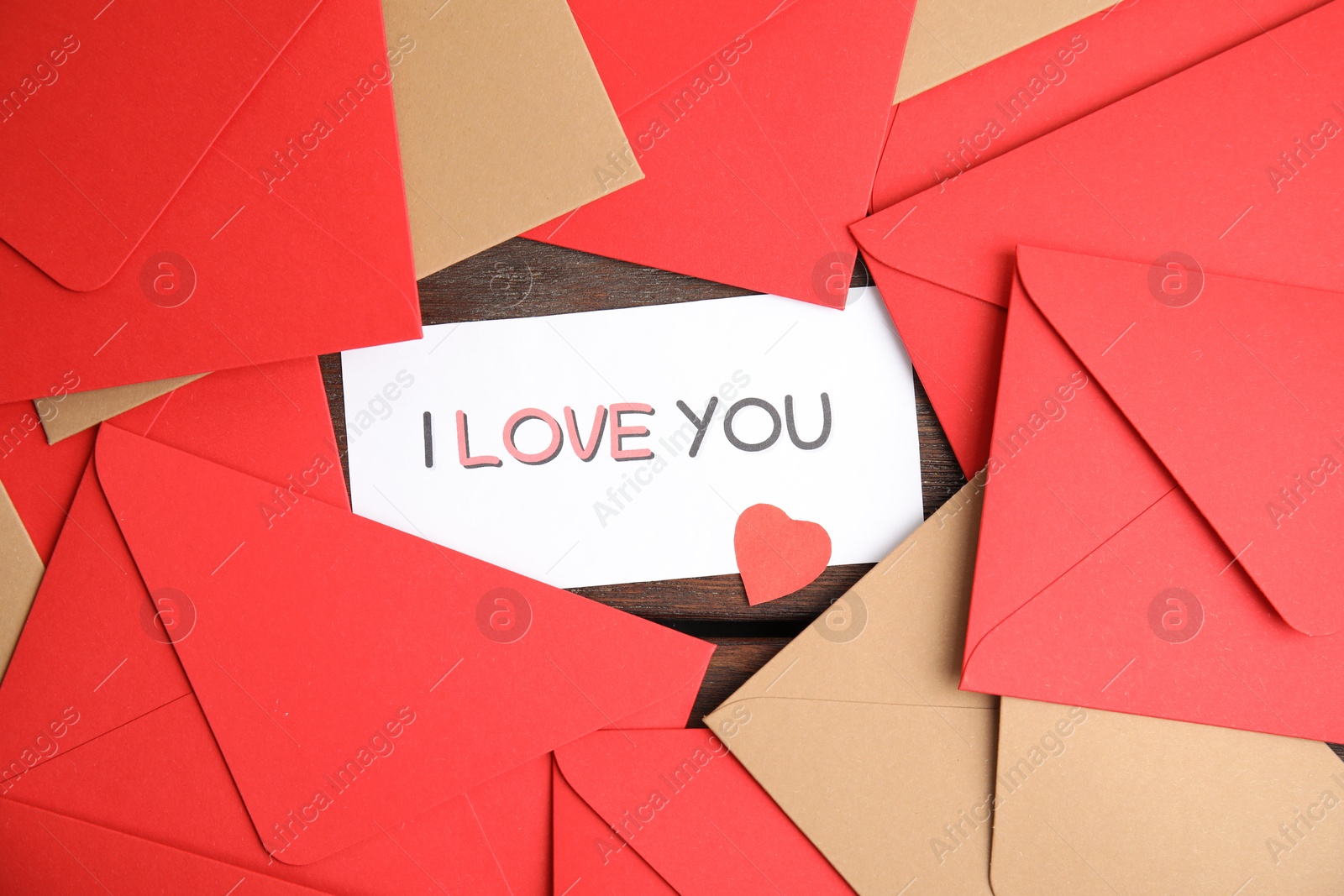 Photo of Card with phrase I Love You, red heart and envelopes on wooden table, flat lay