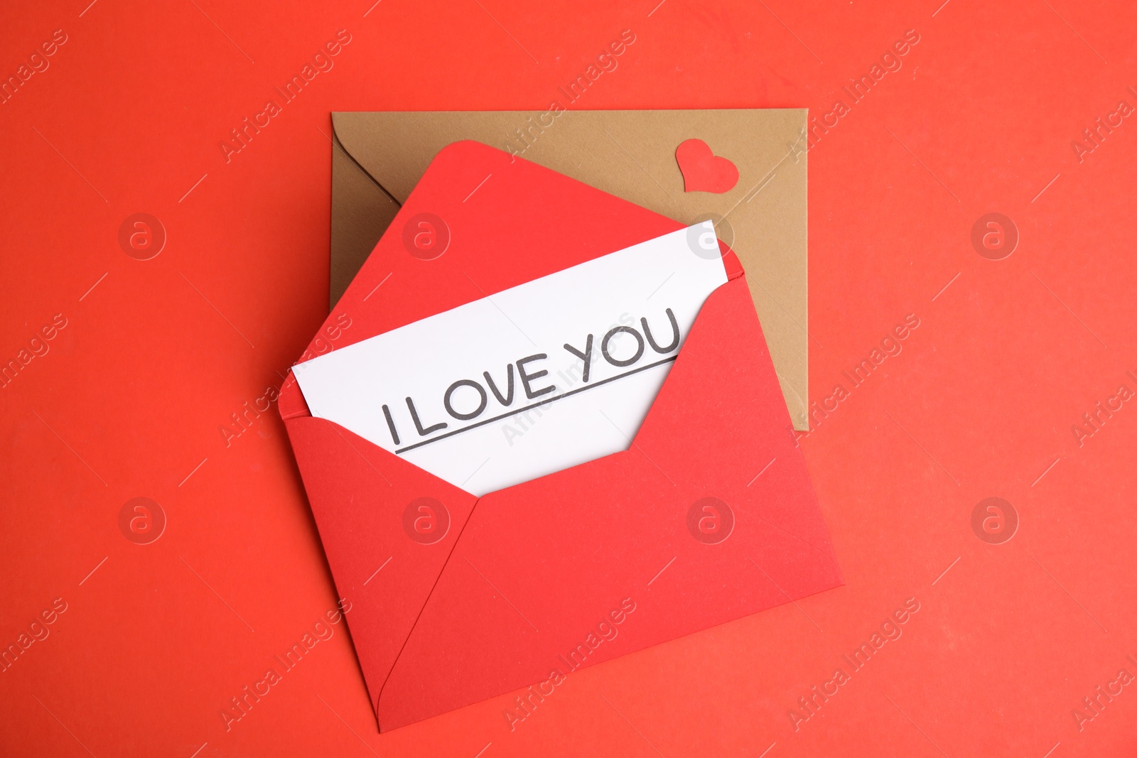 Photo of Card with phrase I Love You in envelope and paper heart on red background, flat lay